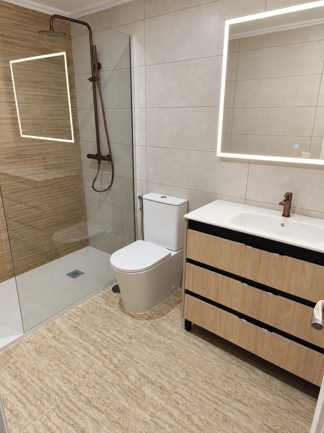 Baño con mampara de cristal, mueble de lavabo y espejo iluminado.