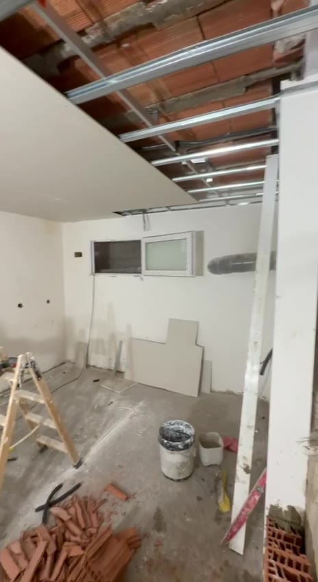 Techo con perfiles metálicos y placas colocándose, paredes blancas y ventana al fondo